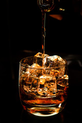 strong alcohol whiskey is poured into a glass with ice closeup