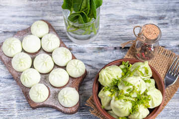 Boiled khinkali made of dough with spinach. Garnished with Red Chilli, Dill and Parsley. On a light...