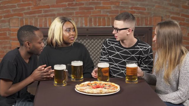Close-up of Afro American and Caucasian couples communicating in pub. Multi-racial friendship concept