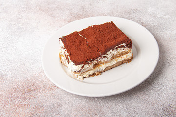 Tasty piece of tiramisu on craft background. Homemade tiramisu closeup.