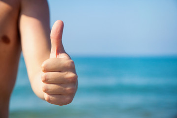 Hand with thumb up on the blue sea background.