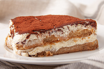 Tasty piece of tiramisu on craft background. Homemade tiramisu closeup.
