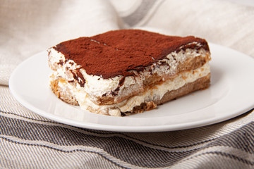Tasty piece of tiramisu on craft background. Homemade tiramisu closeup.