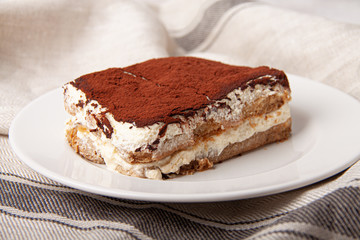 Tasty piece of tiramisu on craft background. Homemade tiramisu closeup.