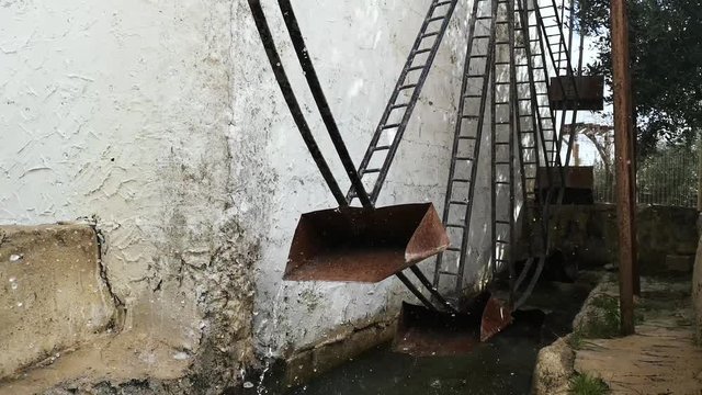 An old rusted watermill in motion beside a rustic building in Europe.