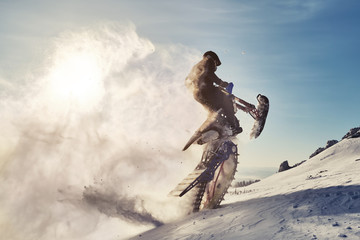 Snowbike rider jumping in mountain valley. Modify dirt bike with snow splashes and trail....