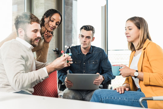 Young business people with laptop and atomic model having a meeting in office