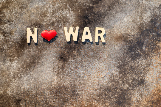 Wooden letters "NO WAR" and red heart shape On the cement background