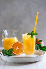 Obraz na płótnie Canvas Natural freshly squeezed orange juice with ice and mint in a glass
