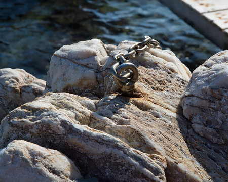 Eye Nut Bolt And Chain.  Rusted heavy duty eye bolt with chain attached to beach rock . Stock Image Isolated Image.