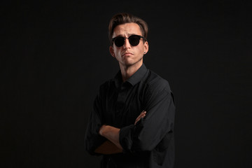 Fototapeta premium Confident stylish man in black eyeglasses isolated over black background.
