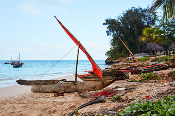 Boat with red sail at the beach