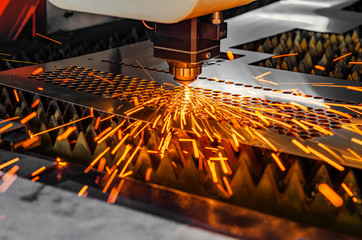 Machine for laser cutting of metal. Laser head cuts the sheet with a beam, sparks scatter in...