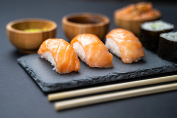 Sushi rolls and sashimi set served on stone slate.