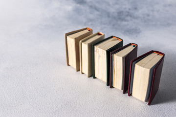 A stack of old little books. Shabby pages, damaged book covers.