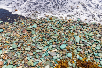 Blue Stones beach with black sand and ocean foam near Ende town, Flores Island, Indonesia