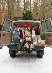Caucasian couple tying fresh cut Christmas tree to a roof of a vintage SUV. Lifestyle, celebration, relationship