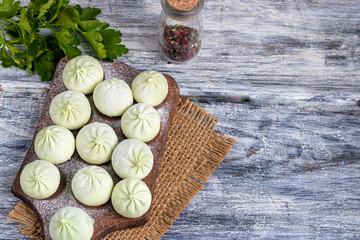 Frozen dough khinkali with spinach. Garnished with Red Chilli, Dill and Parsley. On a wooden background.