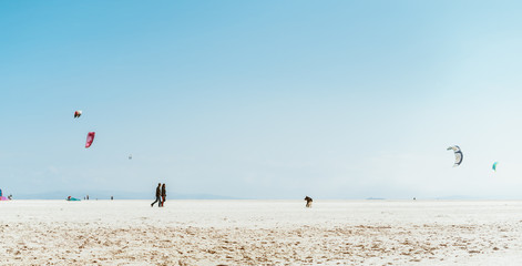 Obraz premium the landscape is a semi-desert beach, kites fly in the distance and figures of three people are visible