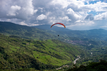 Parapentista sobrevolando las montañas andinas de Colombia en un día soleado