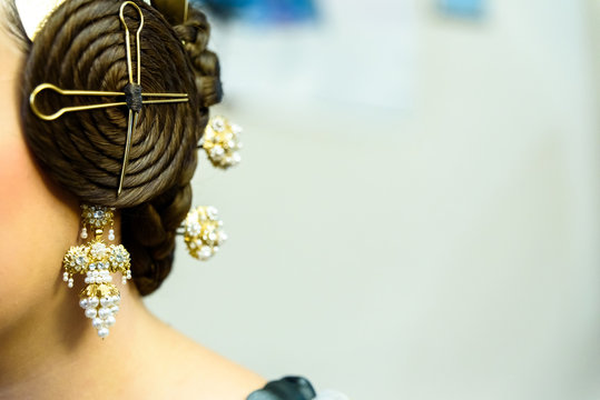 Typical Valencian fallera bun, traditional Spanish hairstyle and decorative earrings, negative space for text