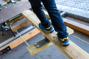 Foot of child doing balances on wooden boards in an urban adventure park.