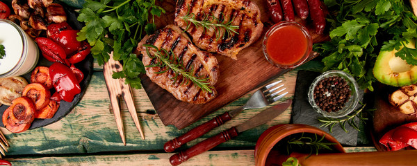 Banner with Steak pork grill on wooden cutting board with a variety of grilled vegetables