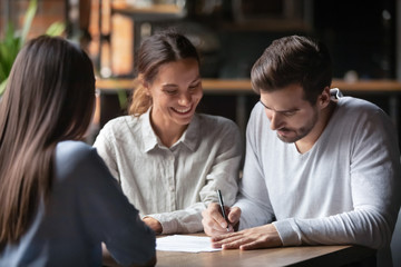 Excited couple closing deal with relator signing contract