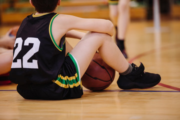 Fototapeta premium Junior basketball player sitting on the floor in backetball court