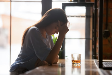 Desperate woman drinking alone suffering from addiction