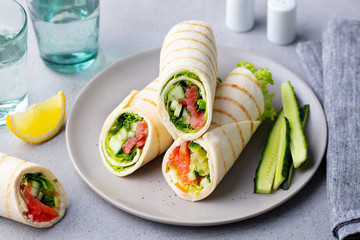 Wrap sandwich, roll with fish salmon and vegetables. Grey background