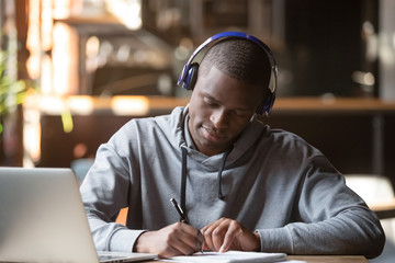 Concentrated black male student in Bluetooth headphones studying