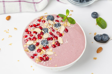 Breakfast smoothie bowl with yogurt, blueberries, pomegranate, almonds and mint. Healthy breakfast