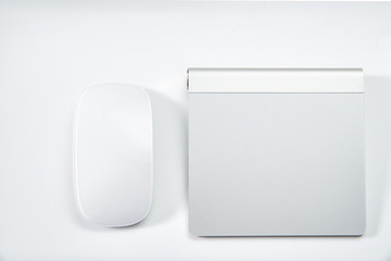 White computer mouse and silver trackpad. The concept of comparing usability, using a trackpad instead of a mouse. Modern computer control methods.