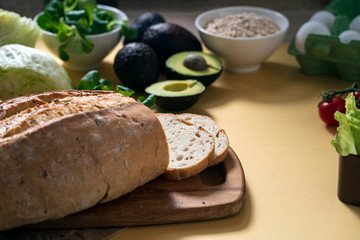 vegetarian breakfast, fresh gluten-free bread, avocado, salad and oatmeal on a yellow background, close-up, horizontal frame, copy space