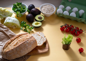 vegetarian breakfast, fresh gluten-free bread, avocado, salad and oatmeal on a yellow background, close-up, horizontal frame, copy space