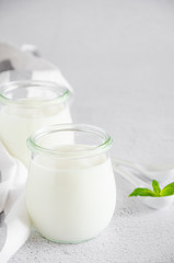 Homemade fresh organic yogurt in glass jars on a light background. Healthy food. Vertical orientation. Copy space.