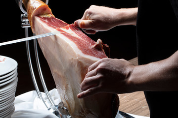 Manos corte de jamón ibérico con cuchillo. Hands cutting Iberian ham with knife.