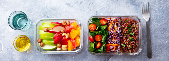 Lunch box with vegetables, brown rice and fruits salad. Healthy eating. Grey background. Top view.