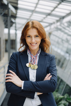 Portrait of a smiling businesswoman wearing medals around her neck in office