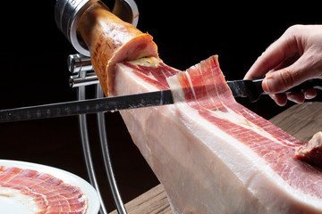 Jamon ibérico mano cortando jamón co cuchillo. Iberian ham hand cutting ham with a knife.