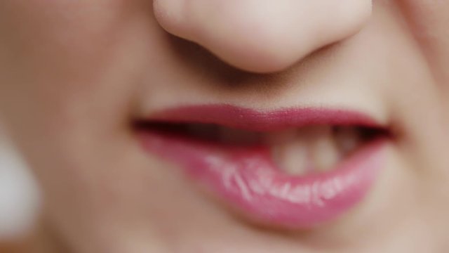 Extreme close up shot of lips.woman with white healthy teeth bitting on the lips with lipstic in slow motion