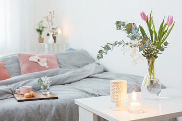 interior of bedroom with flowers, candles and cup of tea