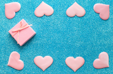 Obraz premium Valentines day pattern background flat lay pink hearts and a pink gift box with rose ribbon on a glittering classic blue background with copy space. love wedding romantic concept, minimal top view