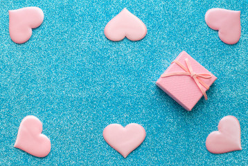 Obraz premium Valentines day pattern background flat lay pink hearts and a pink gift box with rose ribbon on a glittering classic blue background with copy space. love wedding romantic concept, minimal top view