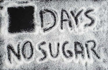 Sugar on a black background top view with text "days no sugar". Design for sugarfree challenge.