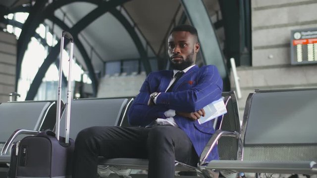 African entrepreneur waiting for delayed train or airplane sitting in waiting area