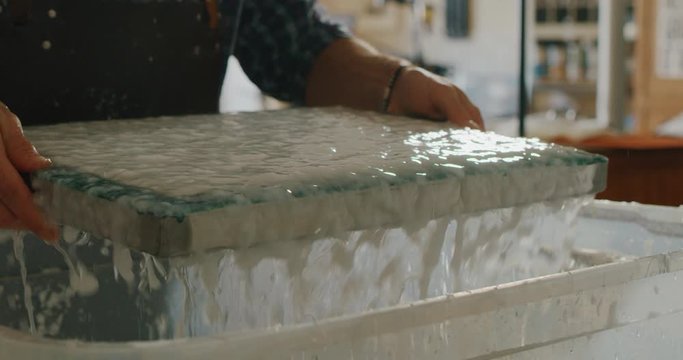 Slow motion close up of artisan papermaking master is working on production of high quality handmade paper in a workshop. Shot in 8K. Concept of handmade,high quality,artisan, made in Italy,tradition