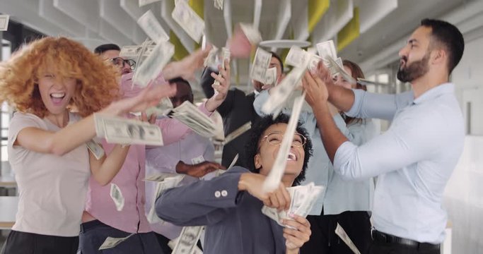 Close up of smiling staff dancing while throwing money at modern office. Team of young diverse coworkers having fun, jumping, rejoicing victory at work space. Concept of successful business.