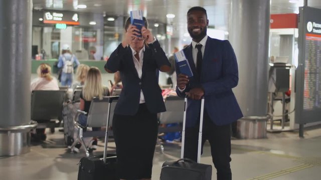 Two cheerful businesspeople dancing with luggage at the international airport